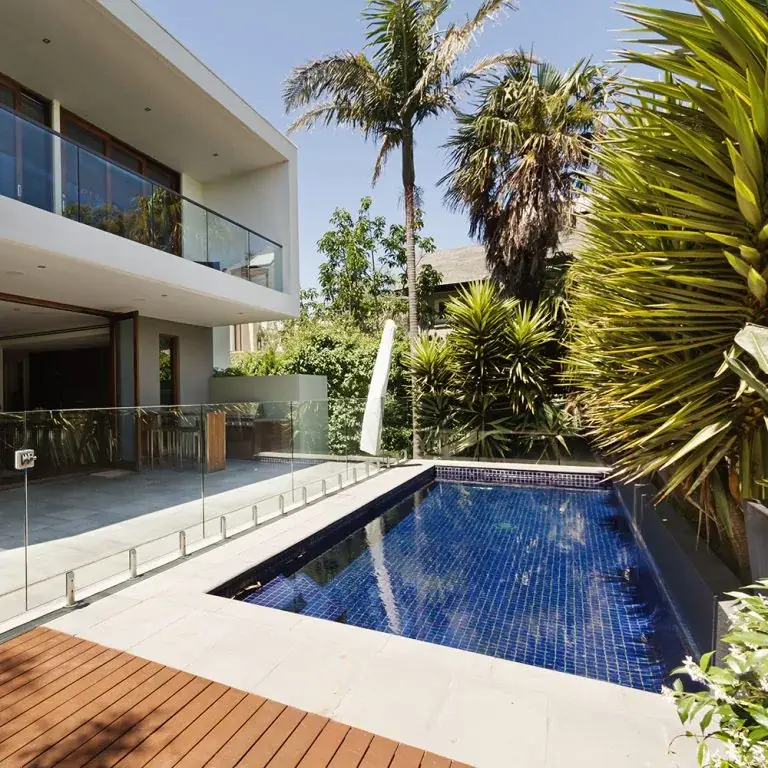 Glass pool fence beside a backyard swimming pool